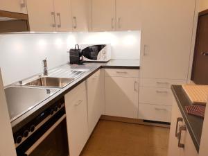 a white kitchen with a sink and a microwave at Apartment Ringstrasse Apt 212 by Interhome in Leukerbad