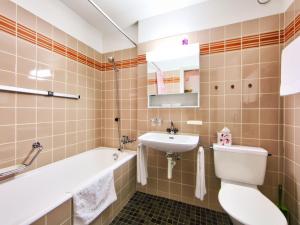 a bathroom with a sink and a toilet and a tub at Apartment Ringstrasse - Utoring-7 by Interhome in Leukerbad
