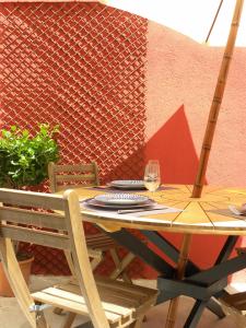 a wooden table with two chairs and a glass of wine at La Terrasse du Marché aux Fleurs in Montpellier