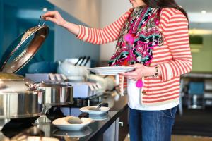 a woman holding a plate in a kitchen at Holiday Inn Express Manchester Airport, an IHG Hotel in Hale