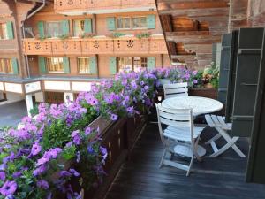 eine Terrasse mit lila Blumen, einem Tisch und Stühlen in der Unterkunft Apartment Le Vieux Chalet by Interhome in Gstaad