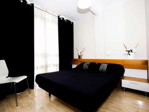 a bedroom with a black bed and a white chair at Apartment Solmar by Interhome in Gandía