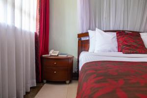 a bedroom with a bed and a phone on a night stand at Desmond Tutu Conference Centre in Nairobi