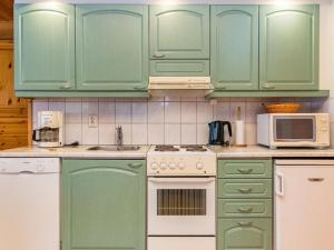 cocina con armarios verdes, fogones y microondas en Holiday Home Ruskatupa by Interhome en Ruka
