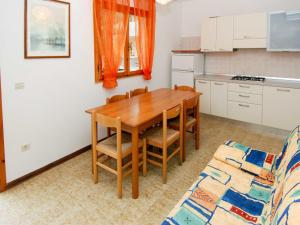 een keuken met een houten tafel en stoelen en een bank bij Apartment Casa Lucrezia-1 by Interhome in Rosolina Mare