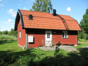 a red house with an orange roof in a field at Chalet Grönede - OST006 by Interhome in Kisa