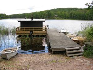 a dock with three boats on a lake at Chalet Grönede - OST006 by Interhome in Kisa