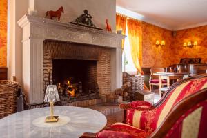 a living room with a fireplace and a table with a lamp at Le Manoir De La Poterie & Spa in Cricquebœuf