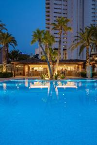 a large swimming pool with palm trees and buildings at Hotel BCL Levante Club & Spa - Only Adults Recomended in Benidorm