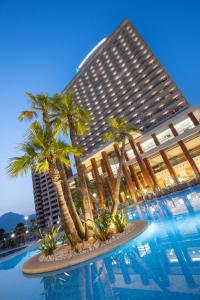 a large building with palm trees in front of a swimming pool at Hotel BCL Levante Club & Spa 4 Sup - Only Adults Recomended in Benidorm