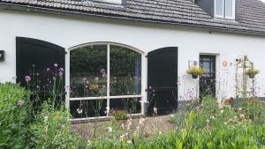 a white house with a black door and flowers at B&B Doremi in Kaatsheuvel
