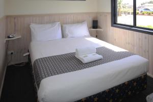 a large white bed with a white towel on it at Sun Country Lifestyle Park in Mulwala