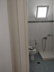 a bathroom with a toilet and a window at Sivilla Budget Studios in Afitos