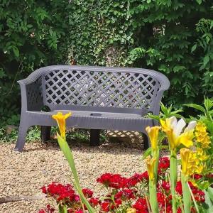 un banco gris sentado en un jardín con flores en Les moineaux du Lileau, en Marchin