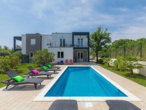 a pool with chairs and a house in the background at Holiday Home Mirna - MDN156 by Interhome in Ližnjan