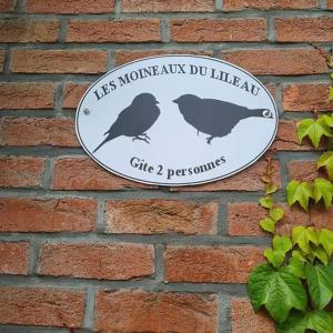 een teken op een stenen muur met twee vogels erop bij Les moineaux du Lileau in Marchin
