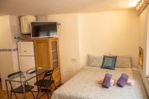 małą sypialnię z łóżkiem z fioletowymi poduszkami w obiekcie Malagueña Salerosa "Apartamento - estudio con terraza" En casa típica de 1 a 4 dormitorios w Maladze