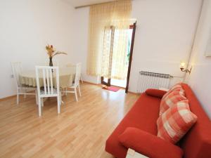 Una sala de estar con un sofá rojo y una mesa. en Apartment Marija by Interhome, en Supetar