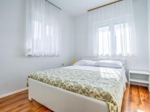 a white bedroom with a bed and two windows at Apartment File-5 by Interhome in Zambratija