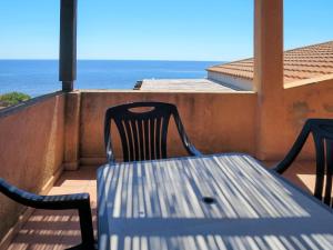 un tavolo e sedie su un balcone con vista sull'oceano di Apartment Il Borgo - PCR215 by Interhome a Villaputzu