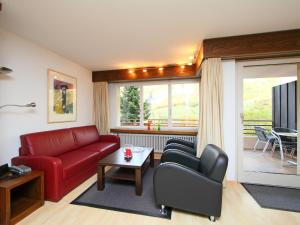 a living room with a red couch and chairs at Apartment Ringstrasse - Utoring-14 by Interhome in Leukerbad