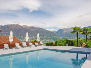 a swimming pool with chairs and a view of the mountains at Apartment Miralago - Utoring-3 by Interhome in Piazzogna