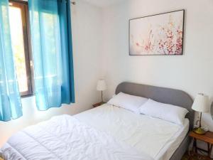 een slaapkamer met een wit bed en blauwe gordijnen bij Apartment Résidence Les Sangliers by Interhome in Saint-Raphaël