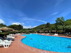 una gran piscina con sillas y sombrillas blancas en Apartment Istrice-10 by Interhome, en Riparbella