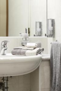 ein Bad mit einem Waschbecken, Handtüchern und einem Spiegel in der Unterkunft Residence I Triangoli in Infernetto