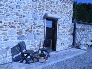 duas cadeiras e uma mesa em frente a um edifício de pedra em A l'orée du Bois em Landelies