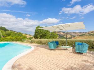 eine Terrasse mit 2 Stühlen und einem Sonnenschirm neben einem Pool in der Unterkunft Holiday Home I Due Carpini-1 by Interhome in Città Sant'Angelo