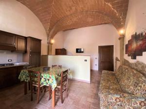 a kitchen and living room with a table and a couch at Apartment Olenadro by Interhome in Montaperti
