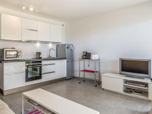 een keuken met witte kasten en een flatscreen-tv bij Studio De la Plage-3 by Interhome in Cavalaire-sur-Mer