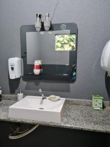 eine Badezimmertheke mit einem weißen Waschbecken und einem Spiegel in der Unterkunft Recanto R-12 in Rodeio Doze