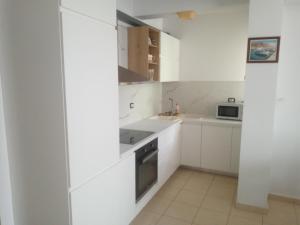 una cocina blanca con armarios blancos y fregadero en Saranda Backpackers, en Sarandë