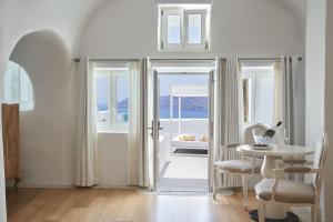 a white room with a table and a view of the ocean at Katikies Kirini Santorini - The Leading Hotels Of The World in Oia