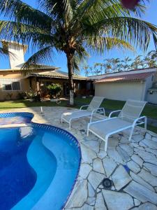 una piscina con 2 sillas y una palmera en Búzios Beach House, en Búzios