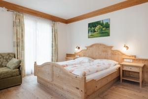 1 dormitorio con cama de madera y silla en Garni Ciasa Urban, en Badia