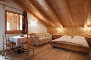 a bedroom with a bed and a table and a couch at Garni Ciasa Urban in Badia