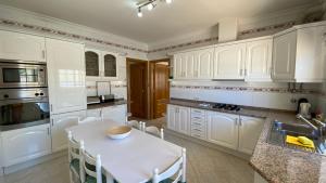 una cucina con armadi bianchi, tavolo e lavandino di Oliveira by Check-in Portugal a Vilamoura