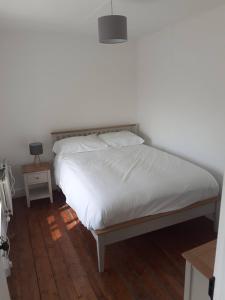 a bedroom with a bed with white sheets and a lamp at Gleann Loic Farmhouse in Dingle