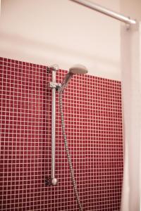 y baño con ducha y pared de azulejos rojos. en B&B Il Guado, en Voghenza