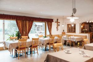 a restaurant with white tables and chairs and windows at Garni Ciasa Urban in Badia