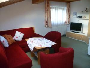 un soggiorno con 2 sedie rosse e una TV di Apartement Obweghof Abtenau, Salzburger Land ad Abtenau