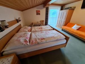 アプテナウにあるApartement Obweghof Abtenau, Salzburger Landのベッドルーム1室(ベッド2台、オレンジ色のソファ付)