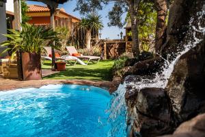 una piscina con cascada en un patio en DELUXE VILLA BELLA VITA AIR CON & HEATED POOL, Tenerife South, en Chayofa