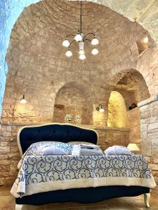a bedroom with a blue bed in a stone wall at Trulli e Puglia Luxury Suite in Alberobello