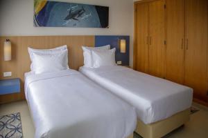 two beds in a hotel room with white sheets at Zephyr Agadir in Agadir
