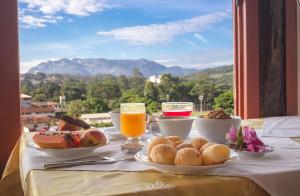 Ein Tisch voller Teller mit Frühstücksspeisen und Getränken in der Unterkunft San Diego Suítes Hotel Quadrado in Santa Bárbara
