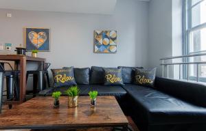 a living room with a black leather couch and a wooden table at The Eistedfod Penthouse - Berwyn House in Wrexham